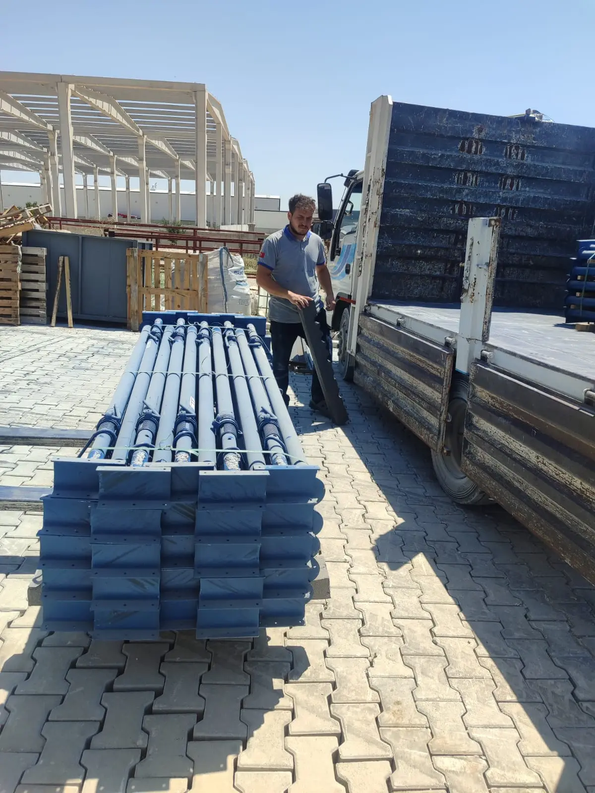 Fabrika sahasında paketli mavi çelik dikmeler ve kamyonet