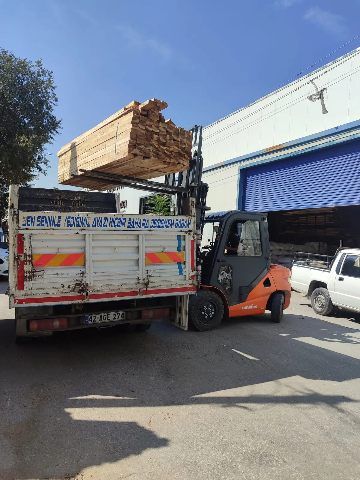 Kereste deposunda forkliftle paketli kerestenin kamyonete yüklenmesi